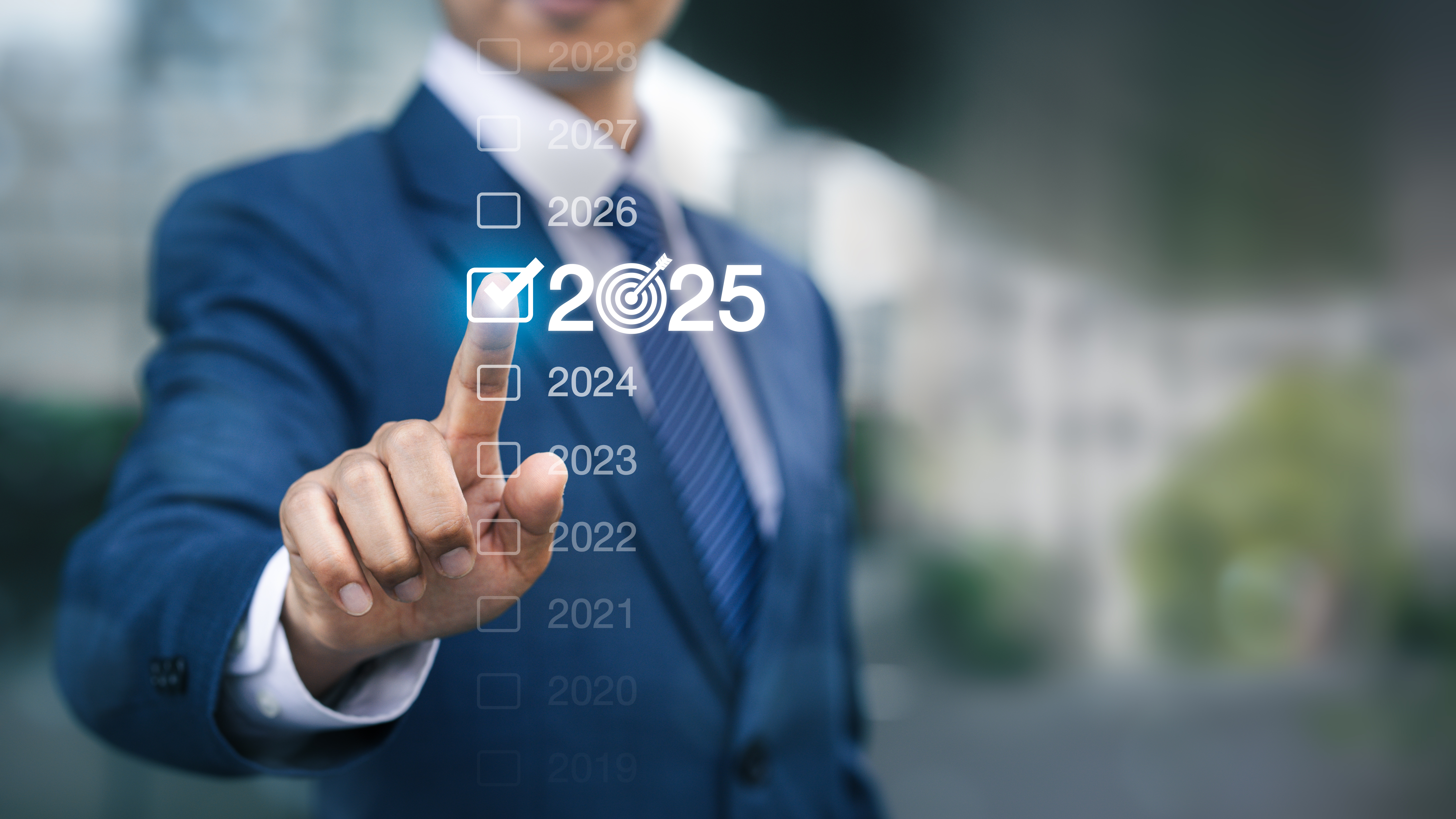 A businessman in a suit pointing at a digital interface displaying a checklist of years from 2019 to 2028. The year 2025 is highlighted with a checkmark and a target icon, indicating a selected goal or milestone for that year.