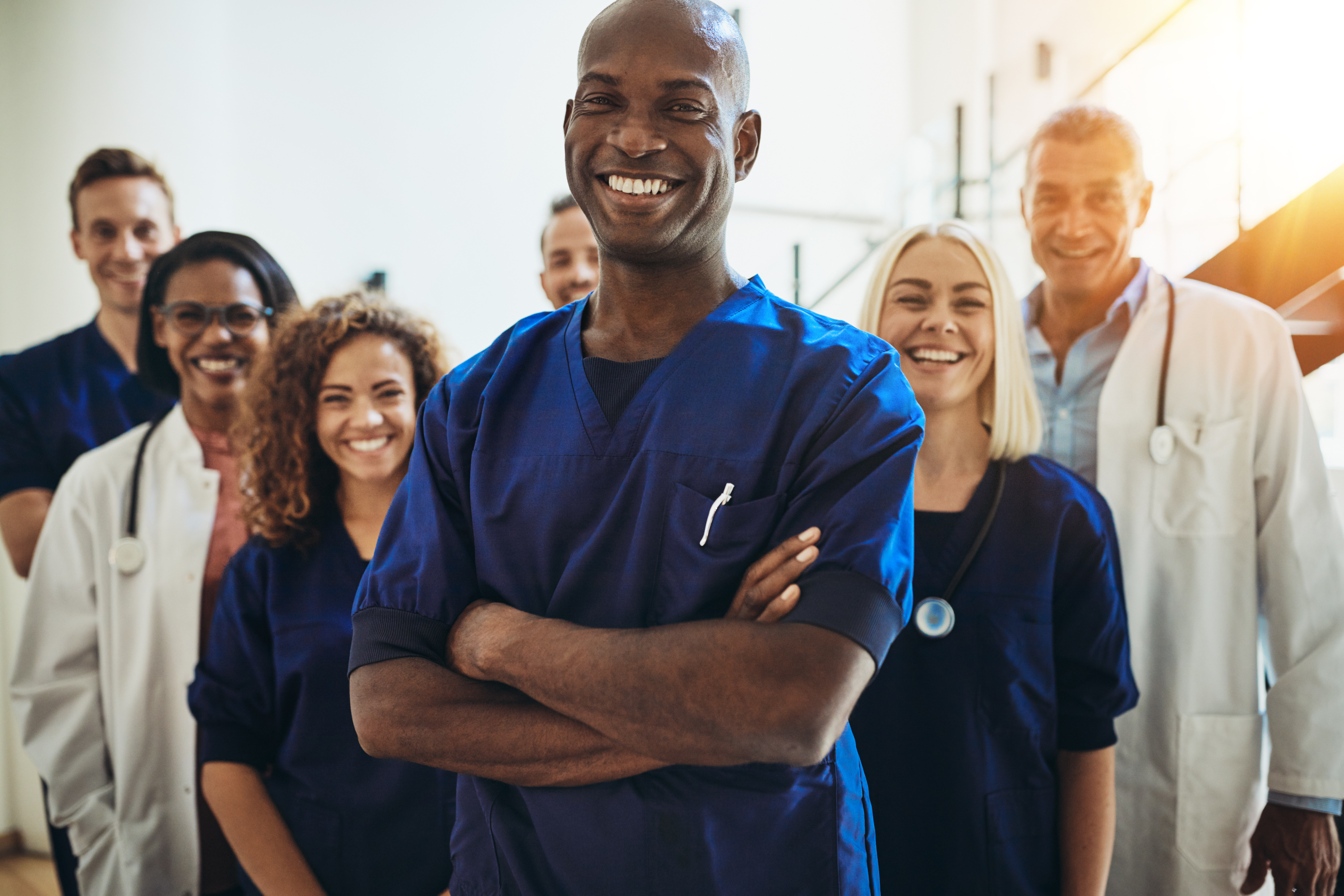 A team of medics smiling and standing together, ready to work. The beautiful sunlight gives them extra energy to work.